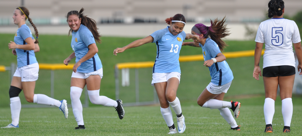 women's soccer team celebrating goal on field