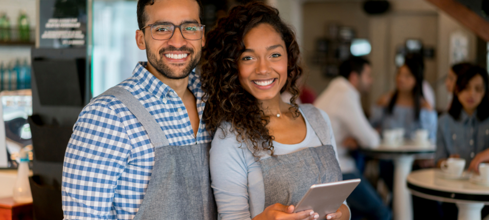 restaurant owners smiling wearing aprons in their restaurant