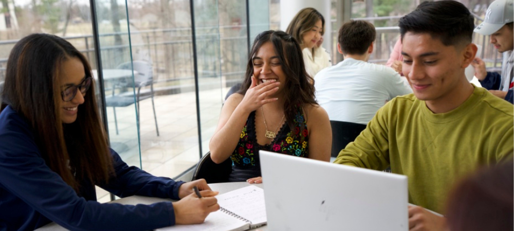 group of students around table laughing while studying