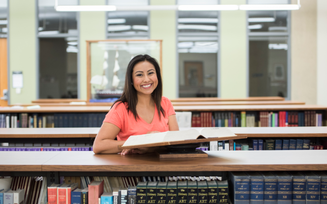 female standing between aisle of books in library